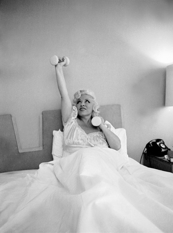 Mae West lifting barbells in bed